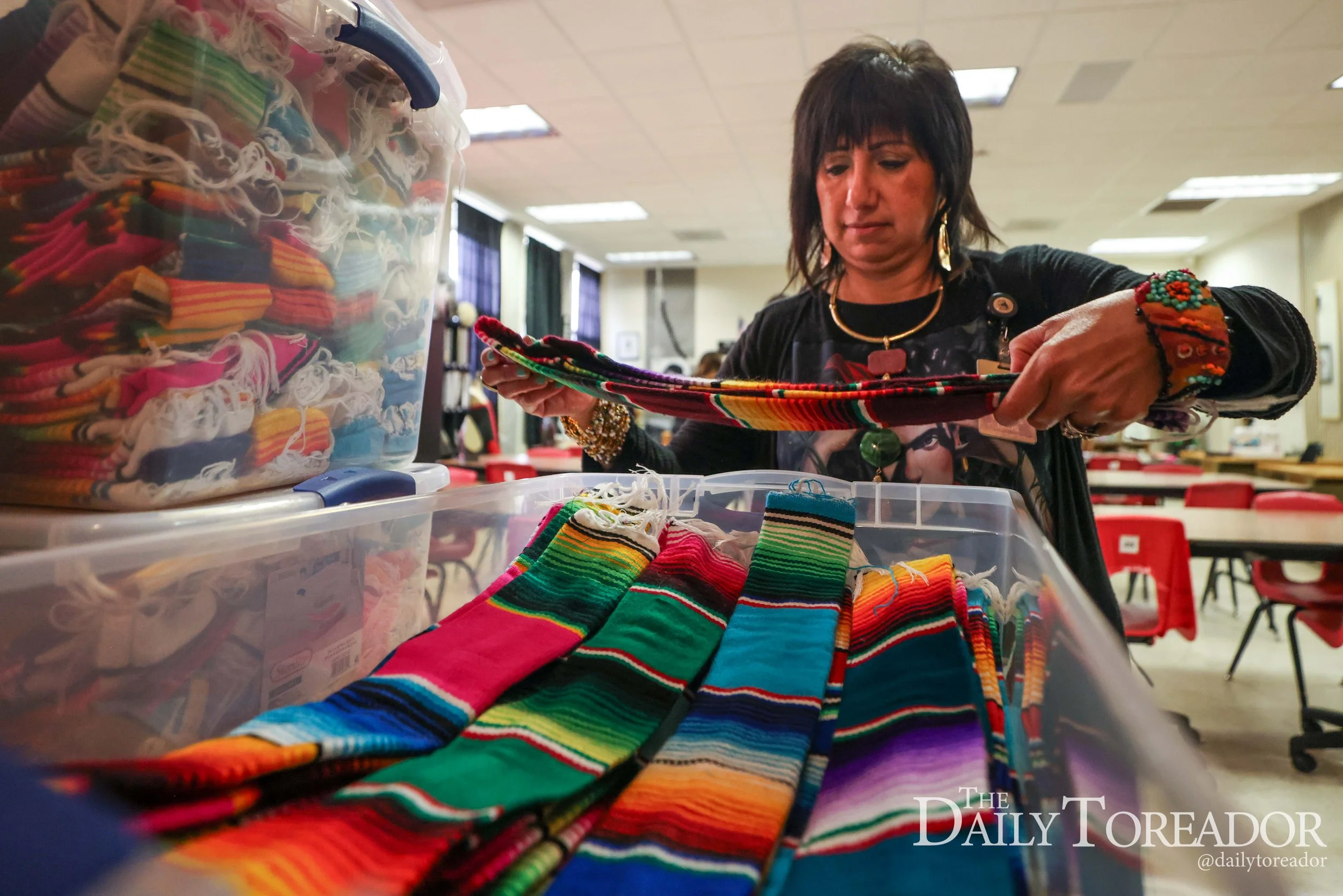A woman looking at colorful striped socks at a table inside a room with fluorescent lights.
