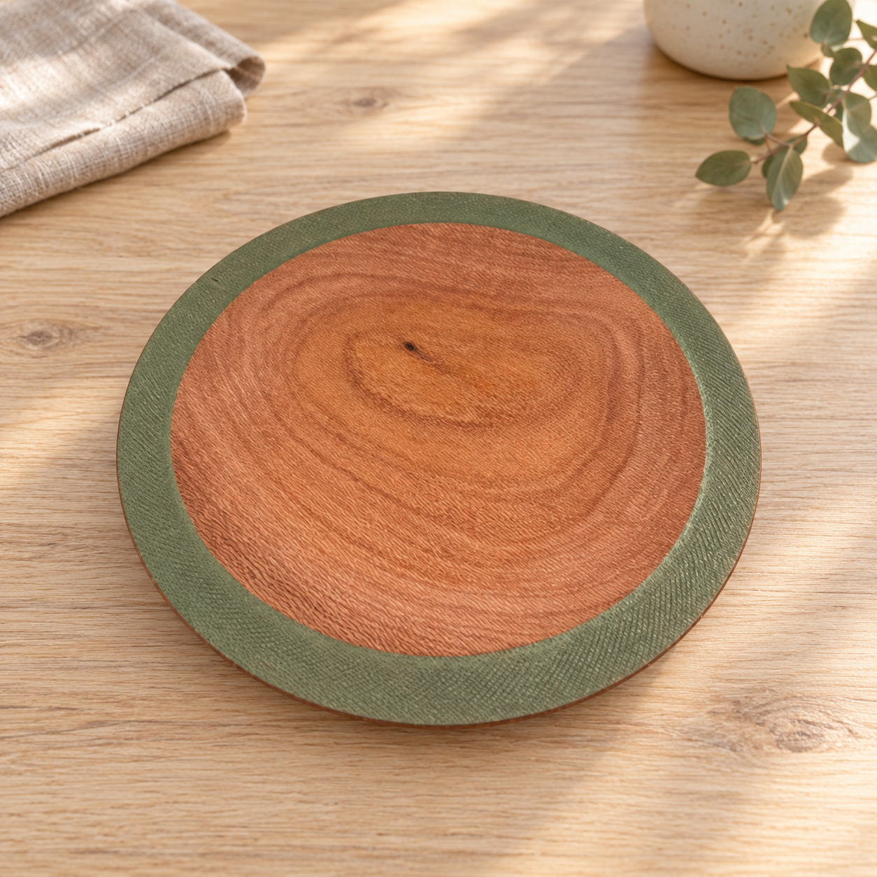 Silky Oak bowl with olive-green rim on a timber table in daylight