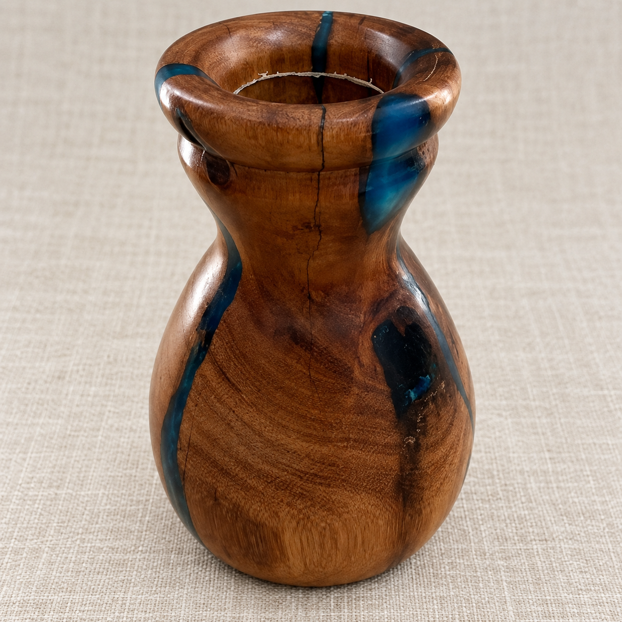 Close-up of blue resin, timber grain and rounded rim of hand-turned vase