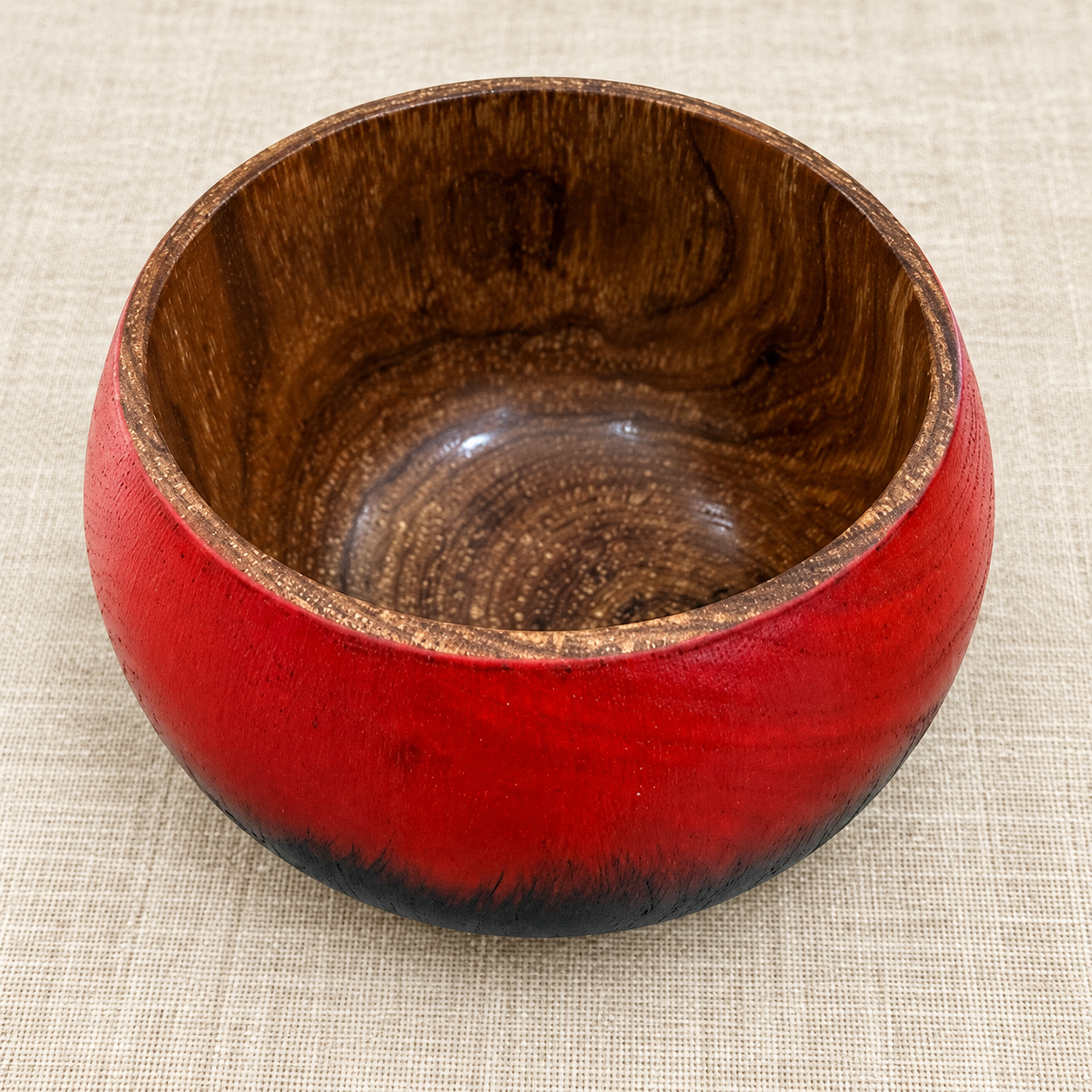 Close-up of natural Silky Oak grain inside a glossy red and black bowl
