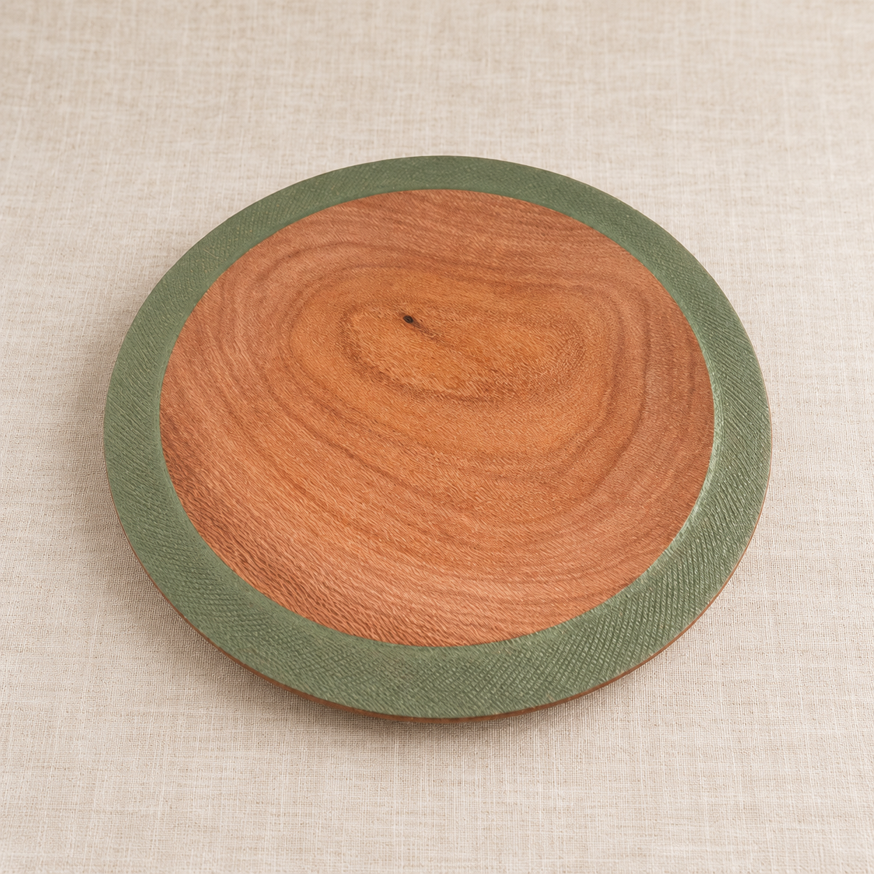 Hand-turned Silky Oak bowl with broad olive-green rim on linen