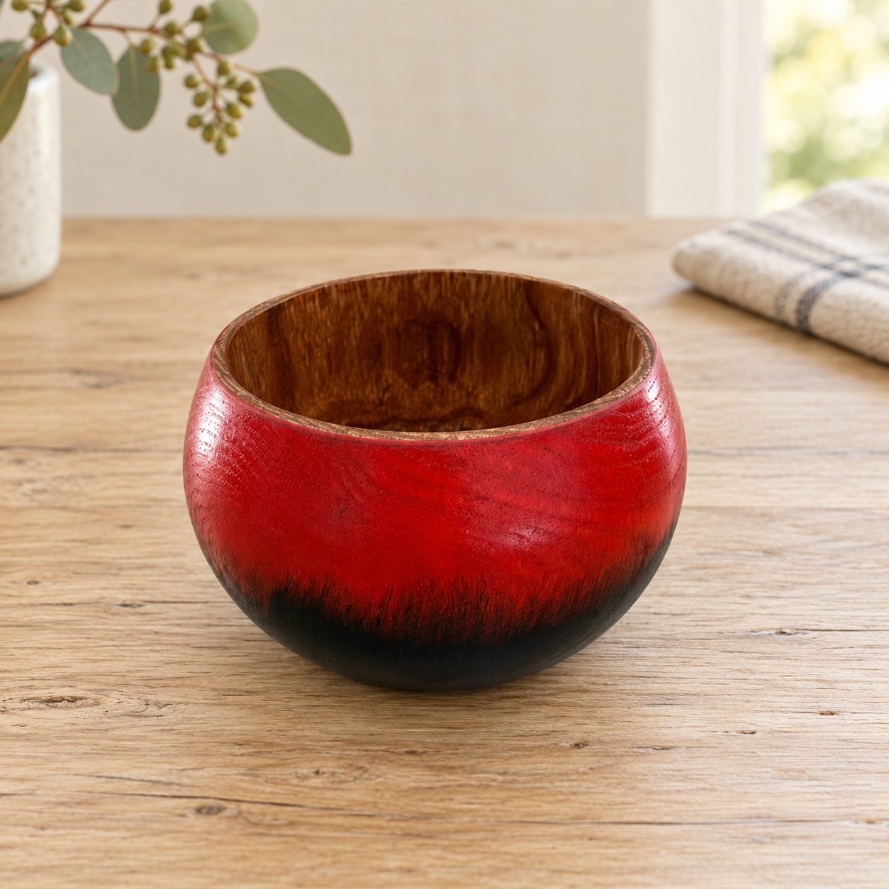 Red and black painted Silky Oak bowl on a timber table in country daylight