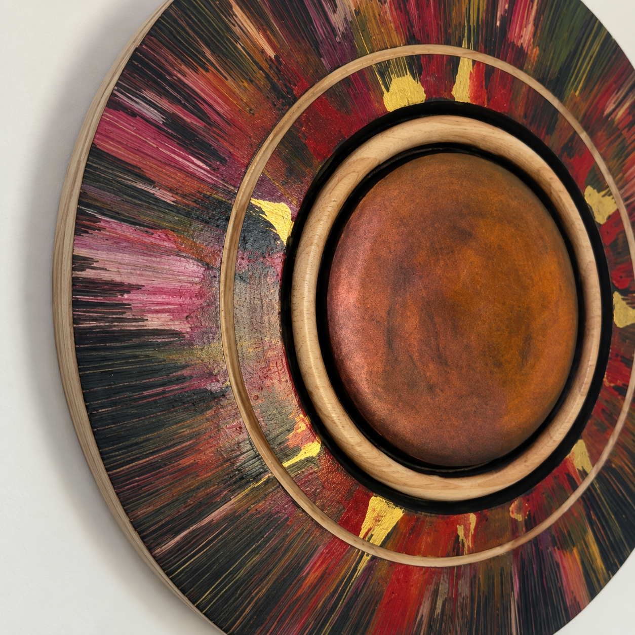 Close-up of the red-toned centre, turned Radiata Pine rings and radiating gold and red wall art detail
