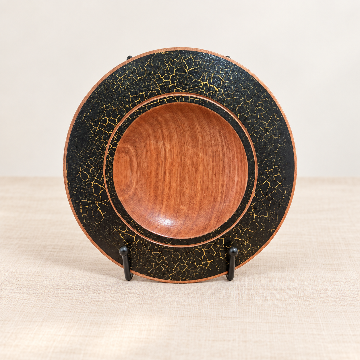 Hand-turned Silky Oak decorative plate with black and gold wrinkle finish on display stand