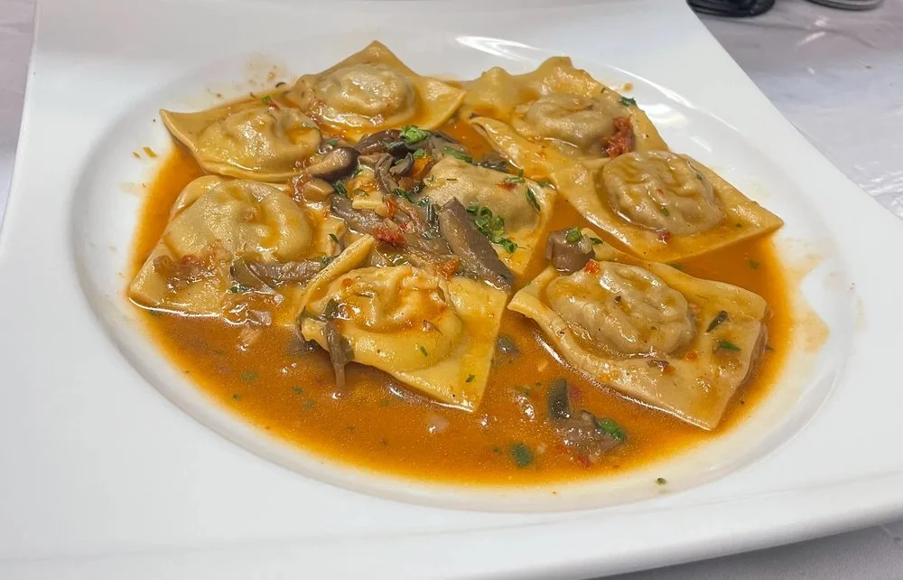 Plate of Chinese dumplings with vegetable and meat filling in a red broth.