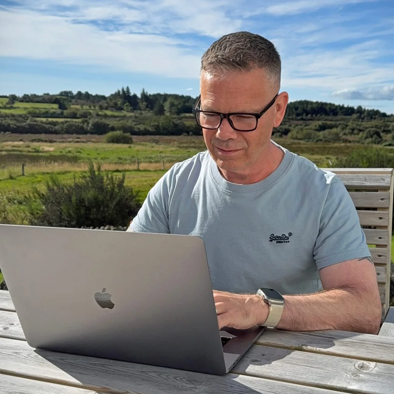 Colin Dobson-Fox writing at his laptop outdoors in the Scottish Highlands.