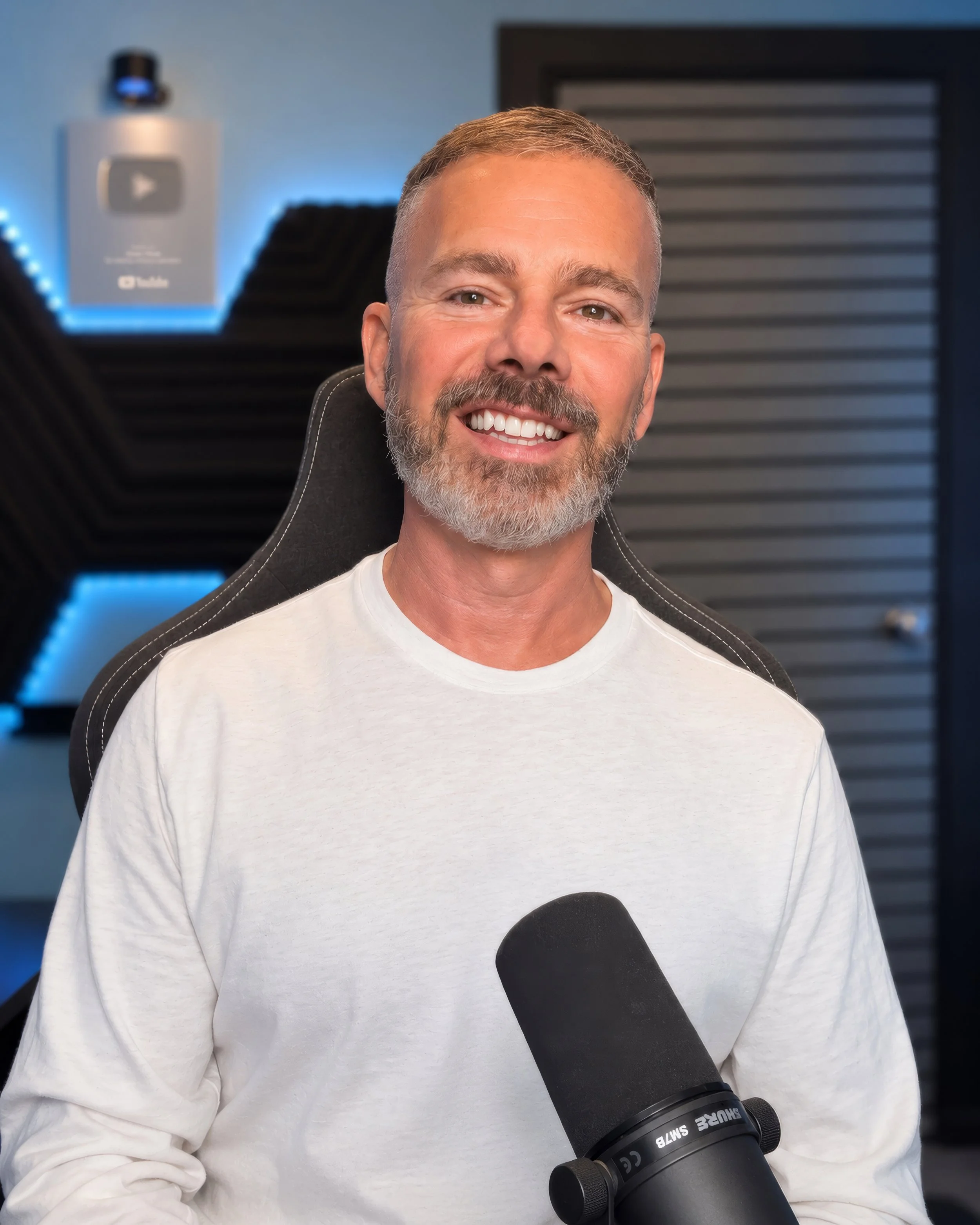 Colin Dobson-Fox in his recording studio with a broadcast microphone and YouTube creator award.