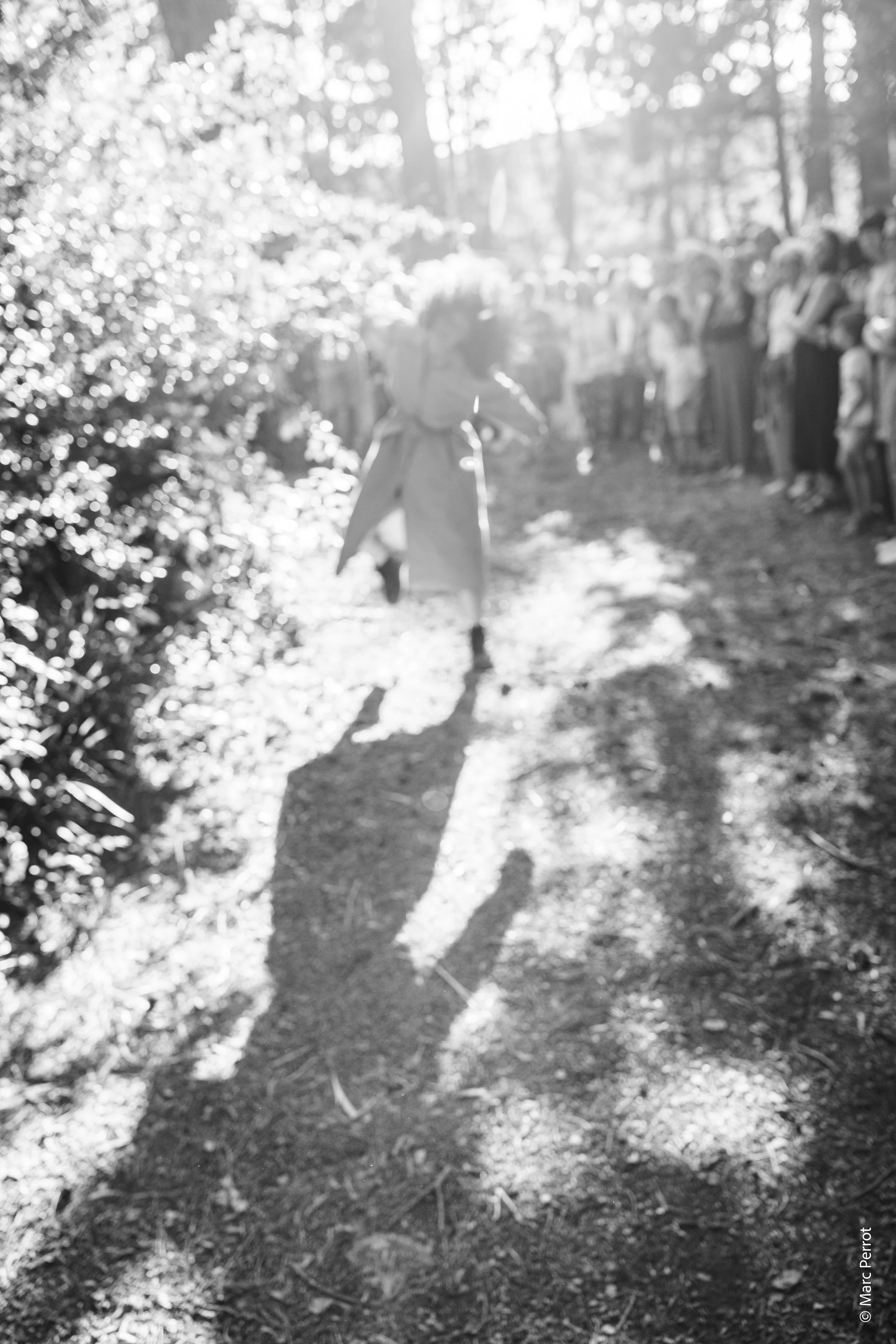 Une silhouette d'enfant courant dans un chemin forestier en rayons de soleil, entouré d'arbres et de végétation.