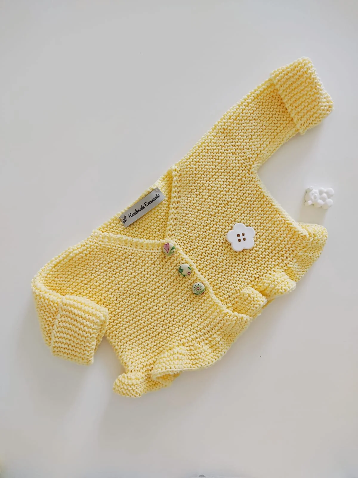 Golfino a maglia giallo con volant sul fondo e bottoni rivestiti in stoffa a fantasia, con etichetta Handmade Emanuela.