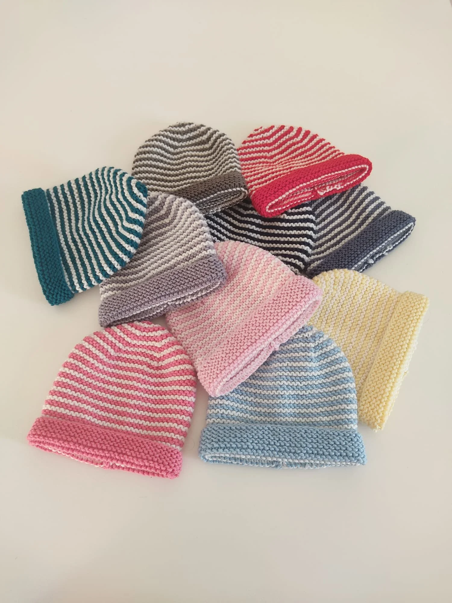 Mucchio di cappelli in maglia a righe sottili bianche, in verde, grigio, rosso, blu, rosa, azzurro e giallo