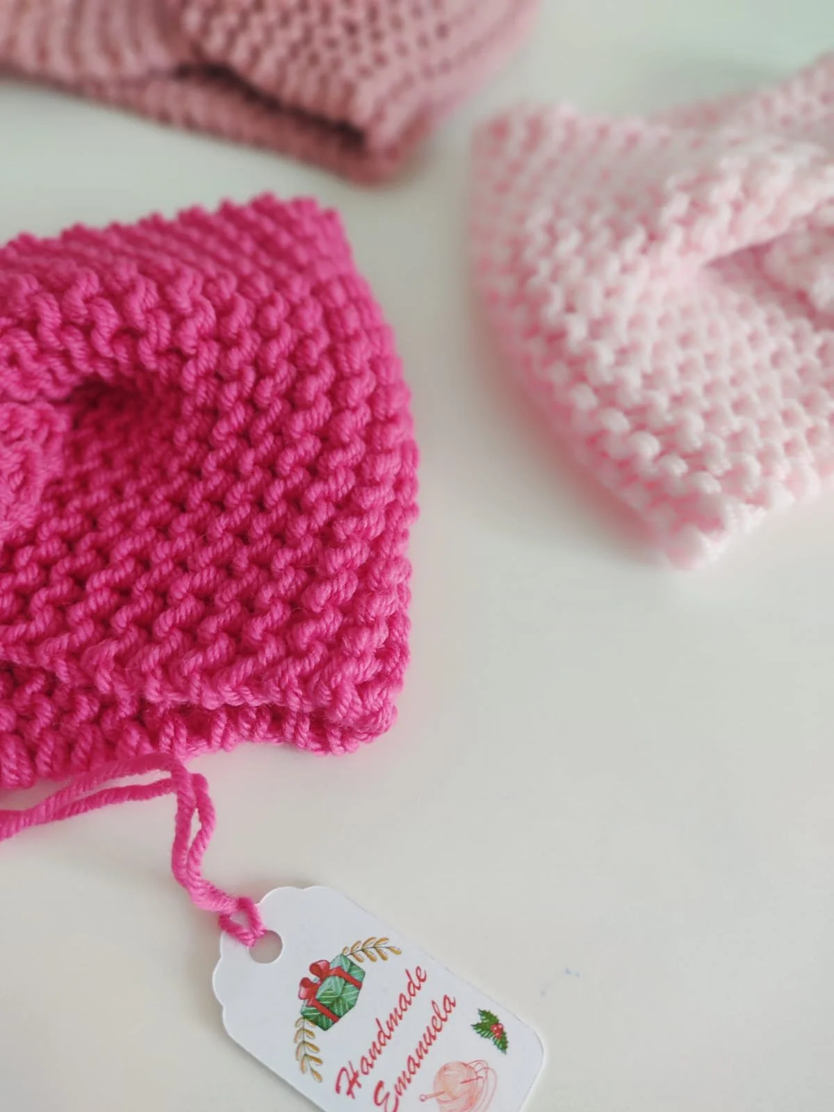 Primo piano di una fascia in maglia fucsia a punto legaccio, accanto a una fascia rosa chiaro