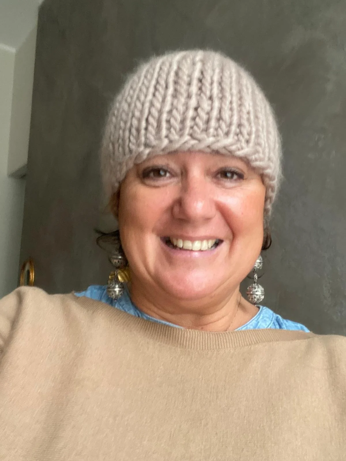 Donna sorridente con cappello in lana grossa tortora a coste larghe