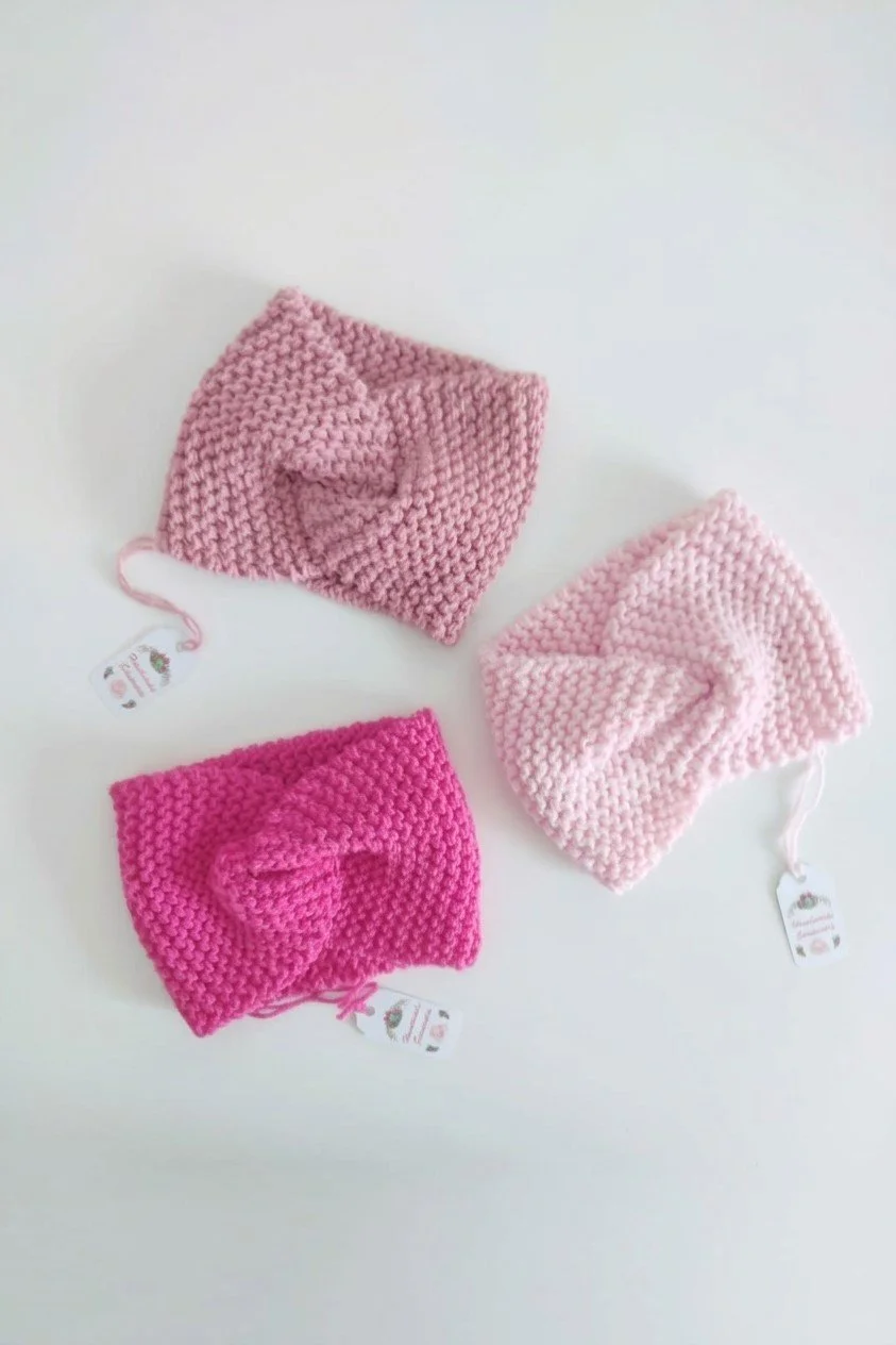 Tre fasce in maglia con nodo incrociato davanti, in rosa antico, rosa chiaro e fucsia, con cartellini