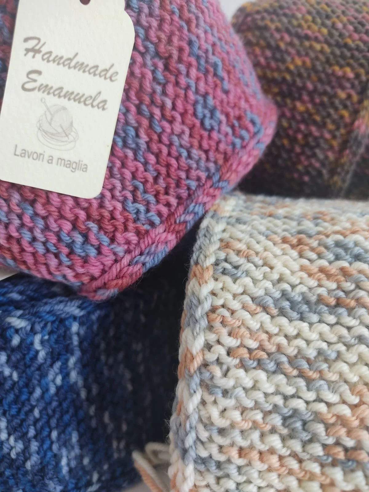 Dettaglio di sciarpe in maglia a punto legaccio in toni mélange rosa e azzurro, blu, beige e marrone