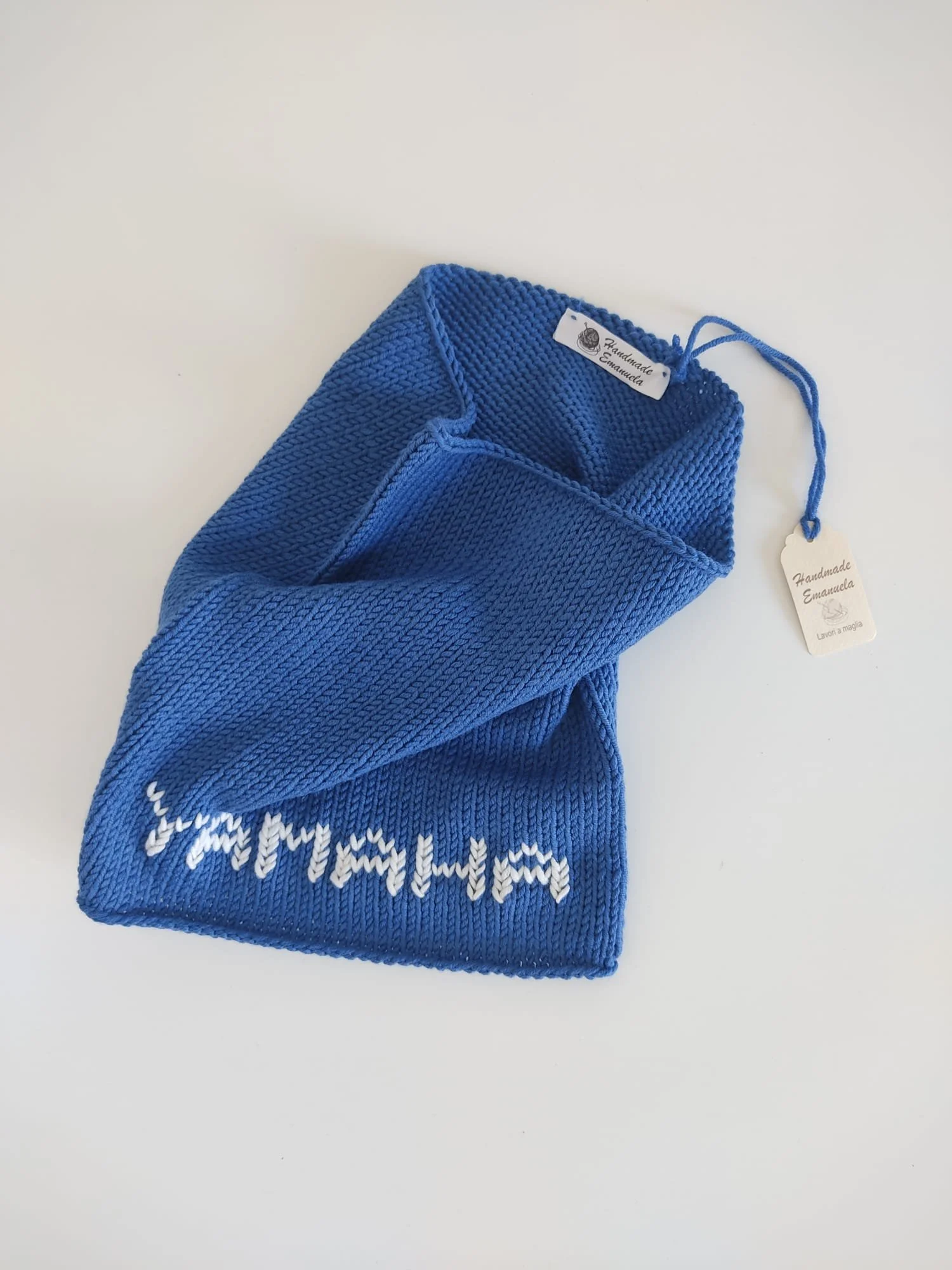 Scaldacollo a maglia blu con una scritta bianca lavorata nel tessuto, con etichetta e cartellino Handmade Emanuela.