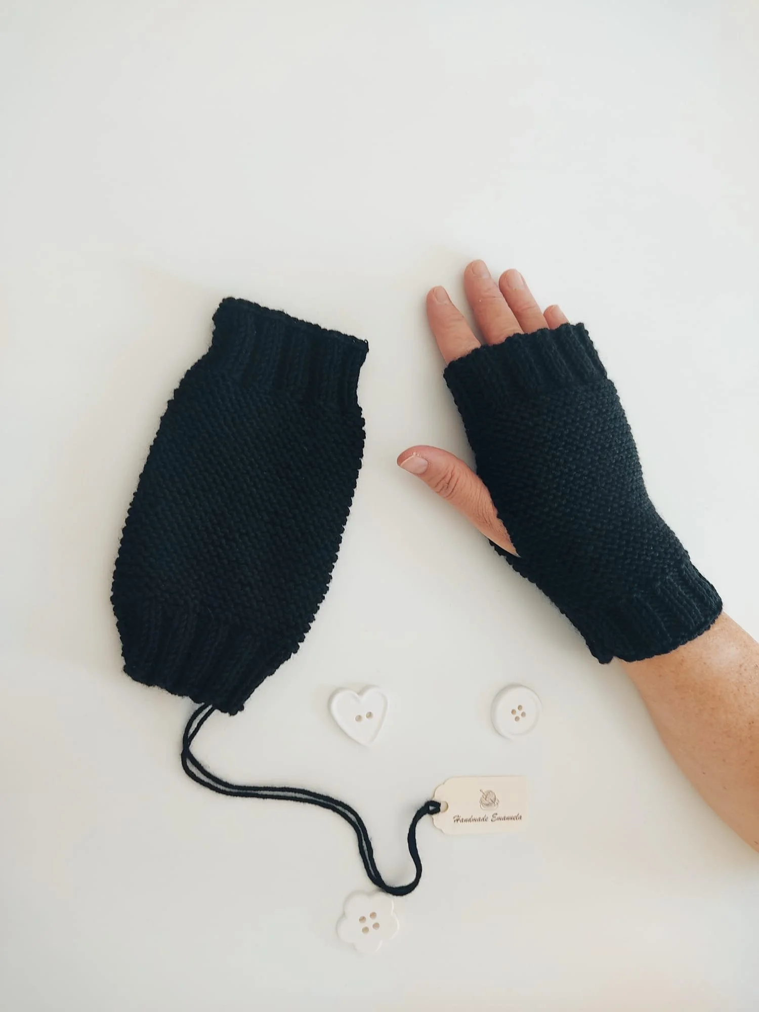 Guantini senza dita in maglia nera a legaccio con polsino a coste, uno indossato, con cartellino