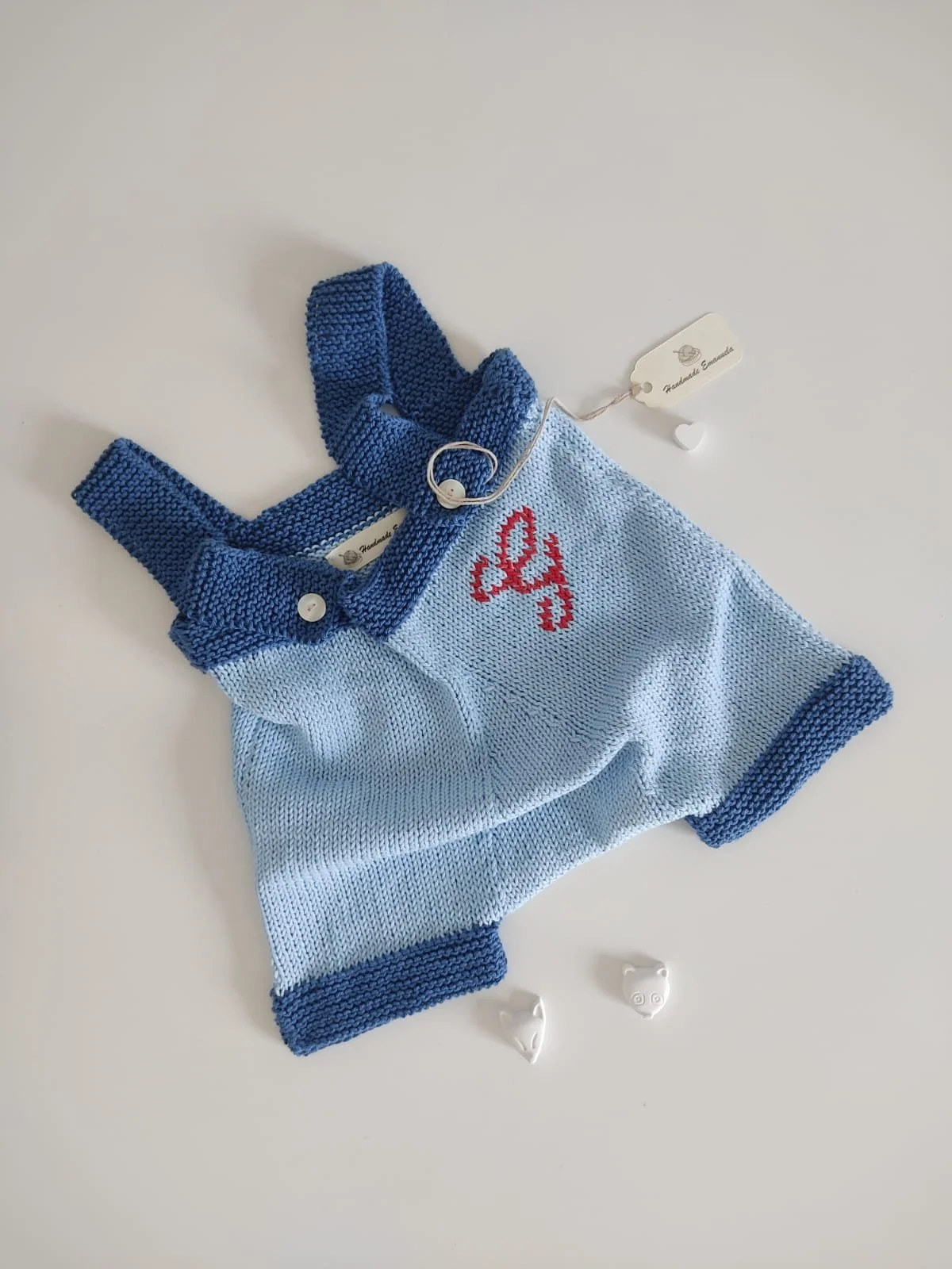 Salopette corta a maglia bicolore azzurra e blu con una lettera rossa lavorata sul davanti e cartoncino Handmade Emanuela.