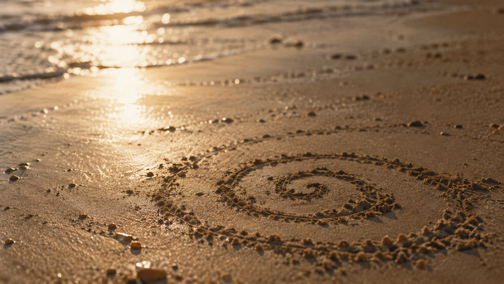 Sand mit Herz und Spiralmuster am Strand bei Sonnenuntergang.