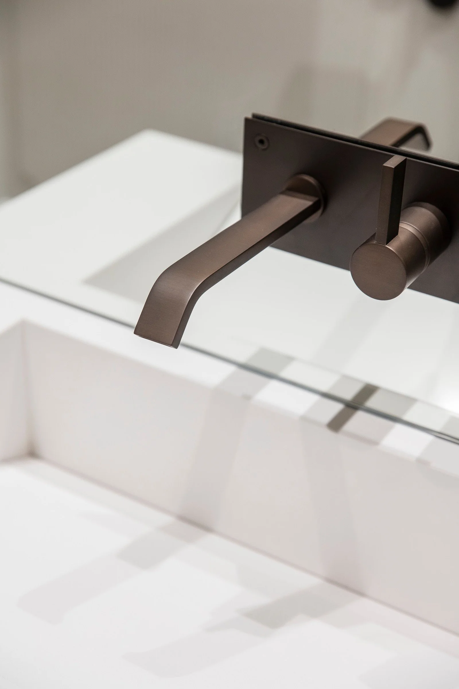 Detalj av mørkt bronse armatur mot lys servant og Calacatta inspirert flis.