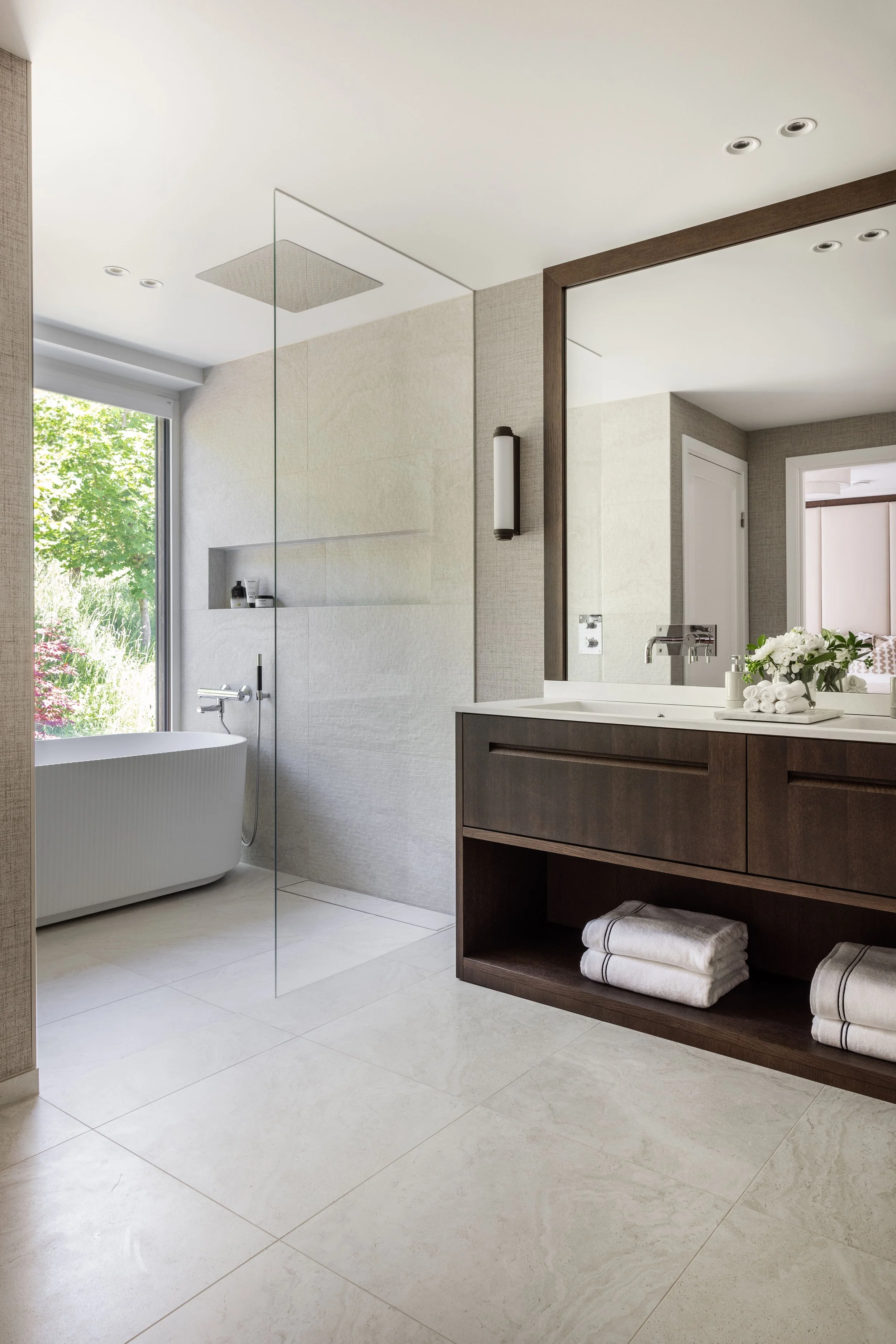 Lyst bad med spesialtilpasset baderomsinnredning, store flater og varme materialdetaljer.