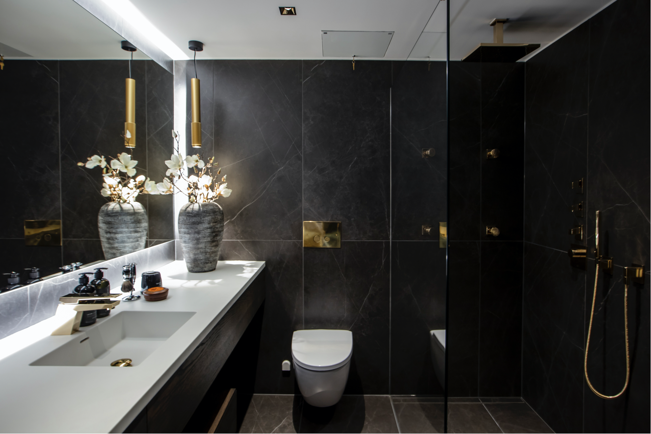 En mørk og sofistikert penthouse i Oslo, designet av Estudio Design, fliser, belysning, dornbracht, spesialdesignet bad, mørke materialer og messingdetaljer.