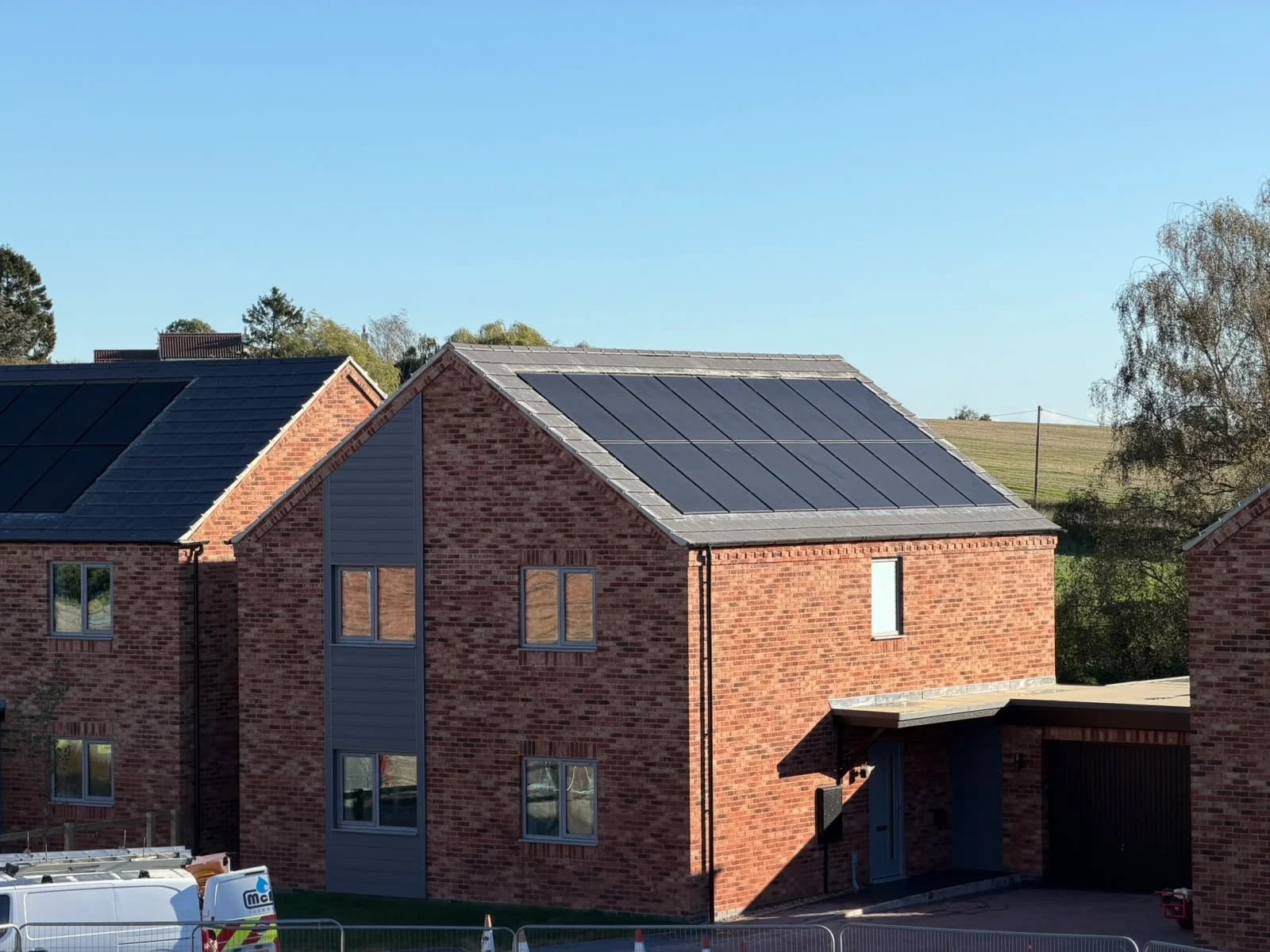 Residential building with brick exterior and solar panels on the roof, under a clear blue sky.