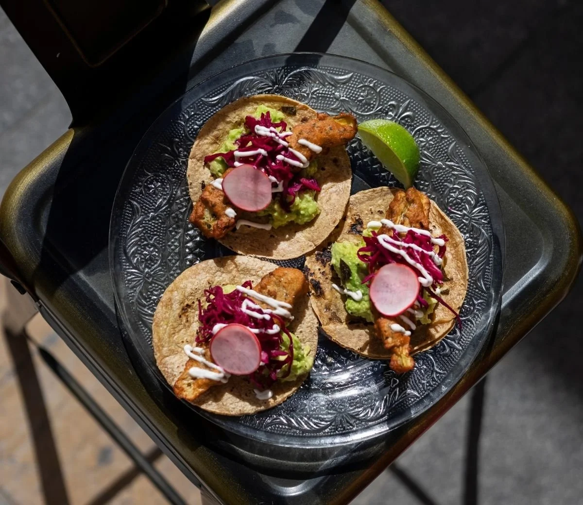 Three tacos topped with guacamole and pickled red onion at Six Seis