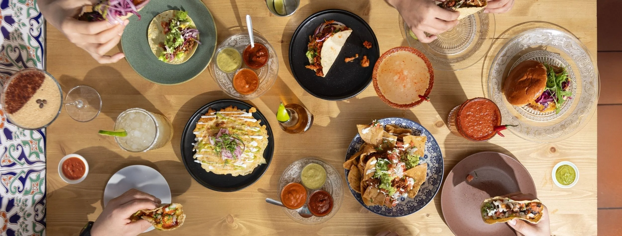 Table of tacos, nachos, quesadillas, salsas and cocktails shared by friends at Six Seis