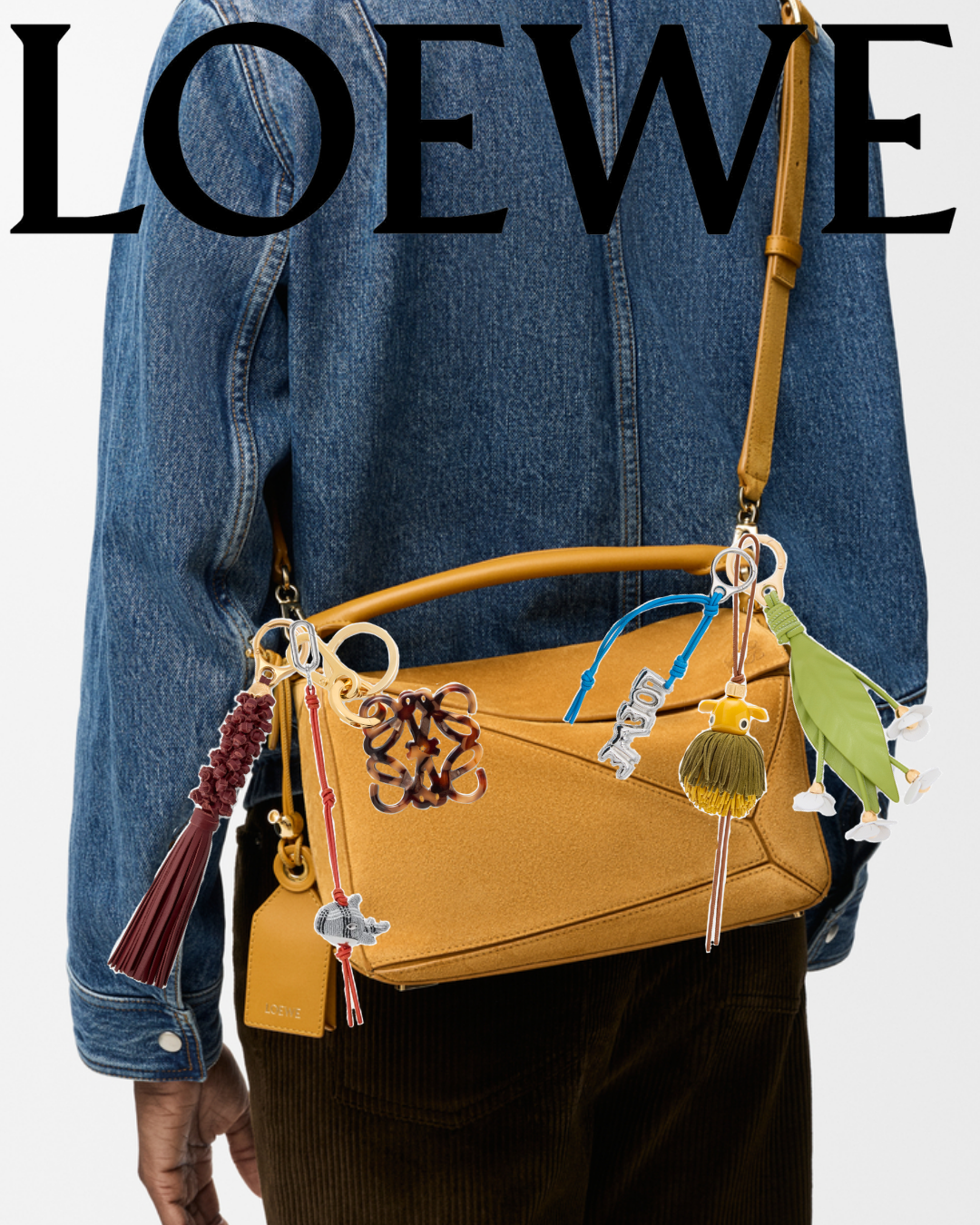 Yellow handbag with colorful charms and accessories, worn over a blue denim jacket and black pants.