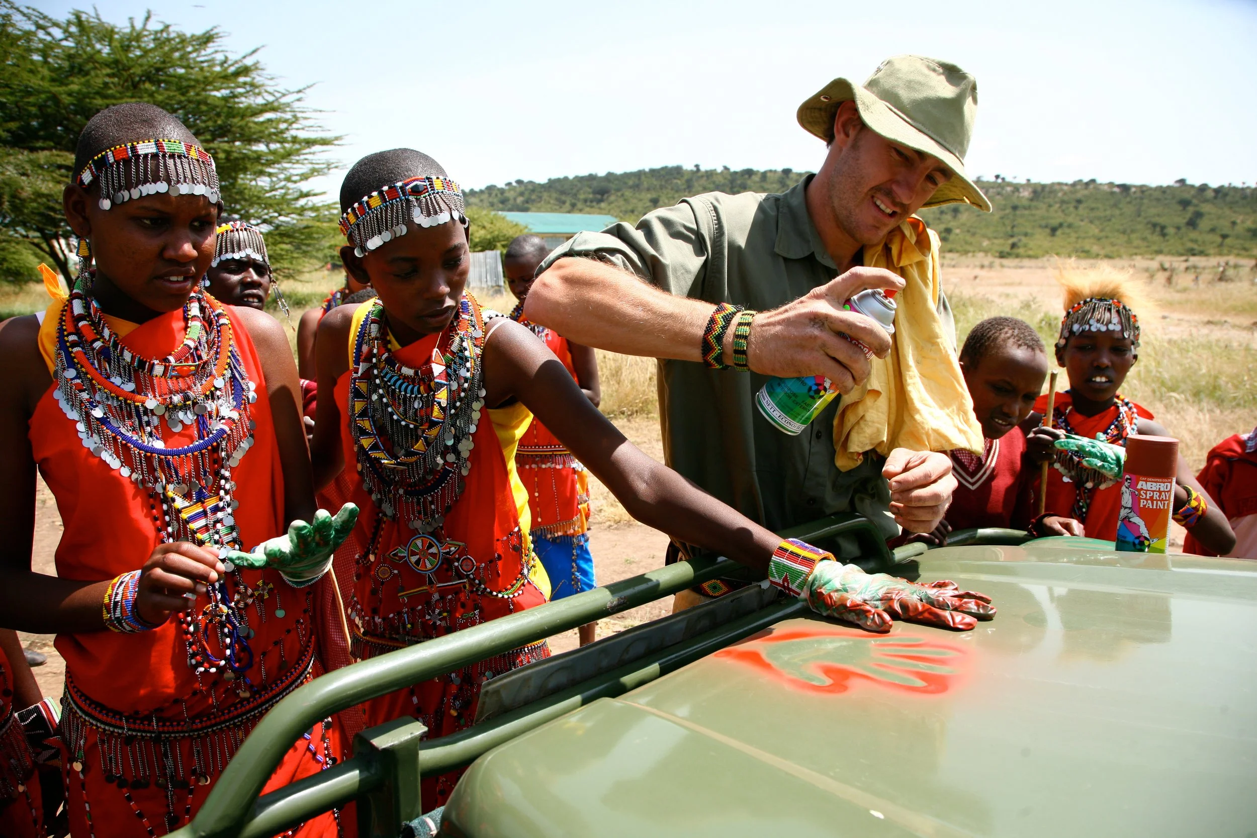A group of Maasai children part of the 'environmental warrior' club at a school in the Maasai Mara sign their commitment to the environment by marking their hands on a vehicle.