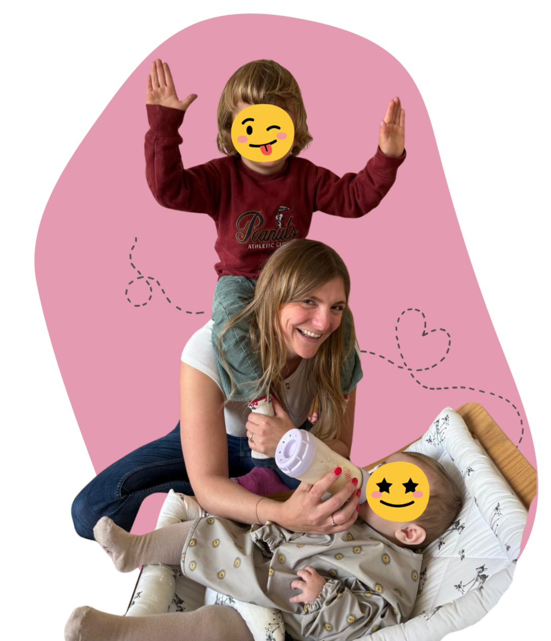 Mère souriante donnant le biberon à un bébé allongé, tandis qu’un enfant debout derrière lève les bras, sur fond rose.