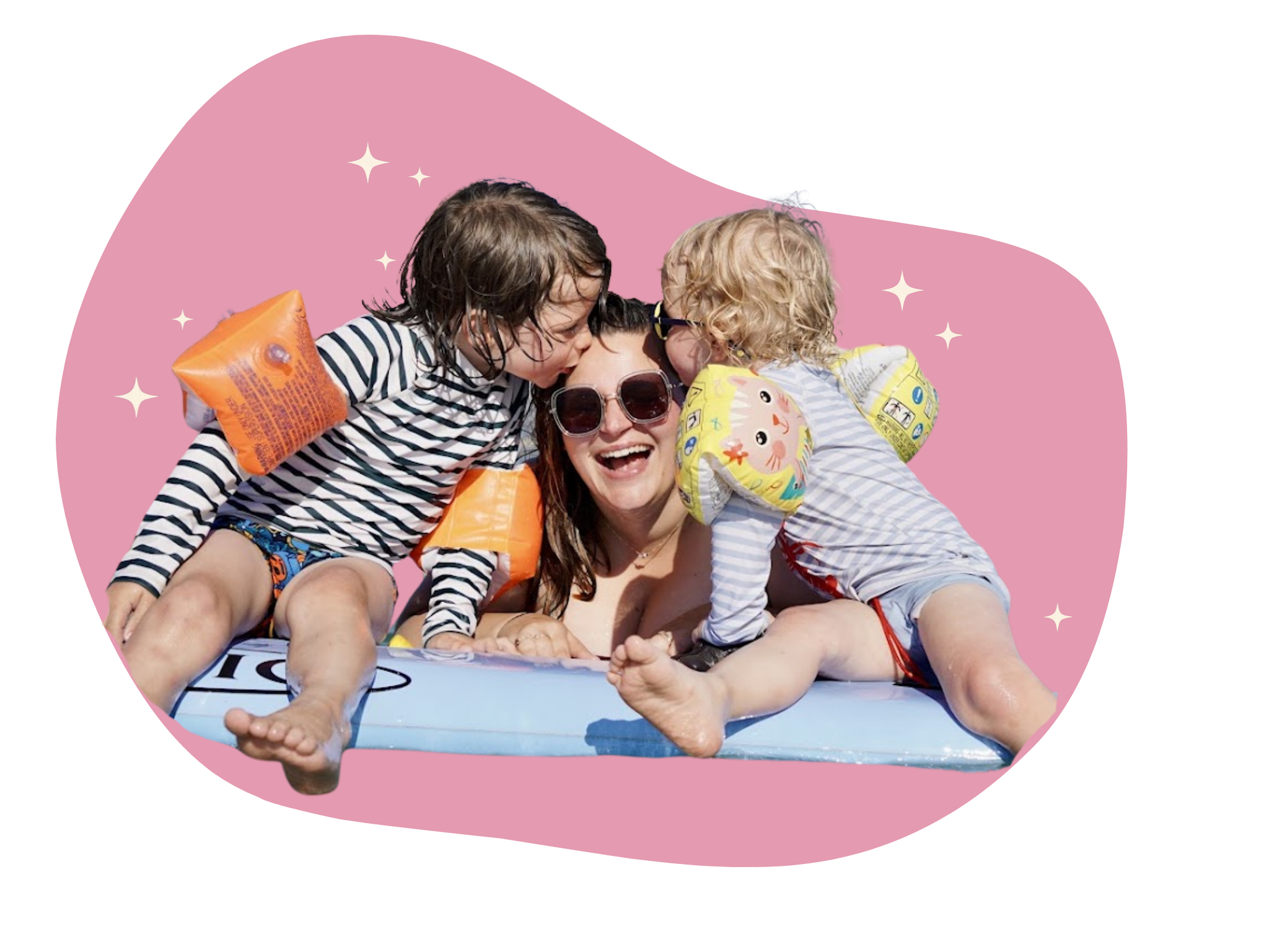 Une mère souriante avec deux enfants en maillots rayés, portant des brassards et jouant dans une piscine.