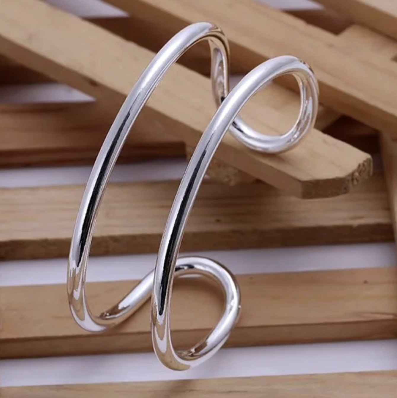 Silver earrings hanging on a wooden surface.
