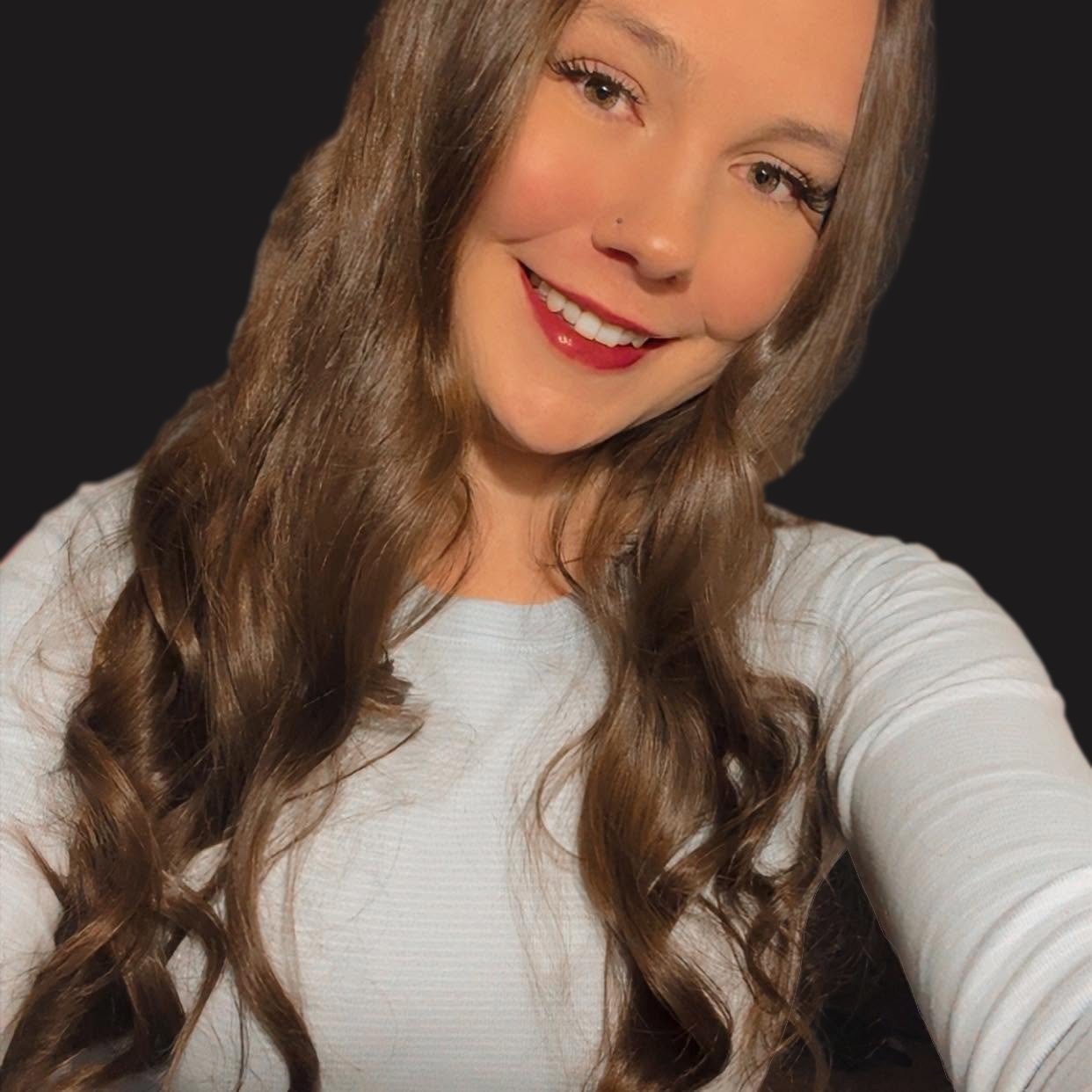 photo of caucasian woman with brown hair smiling wearing red lipstick and white shirt against a black background