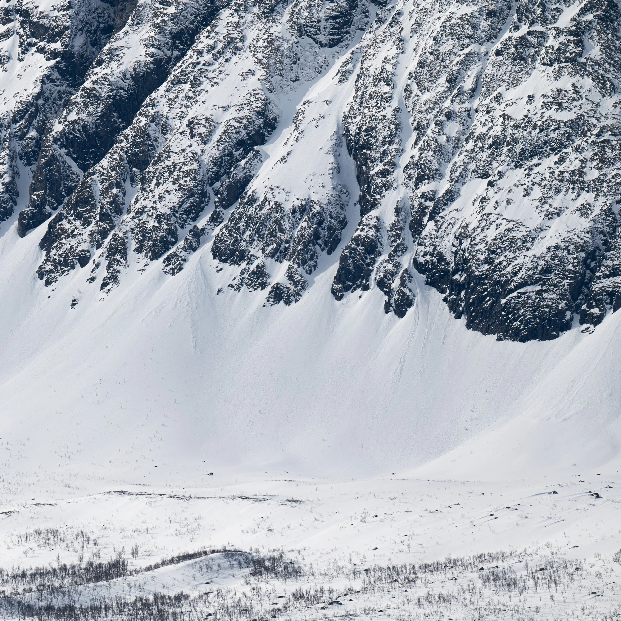 Vue de montagnes enneigées avec des rochers escarpés et une vallée enneigée en premier plan.