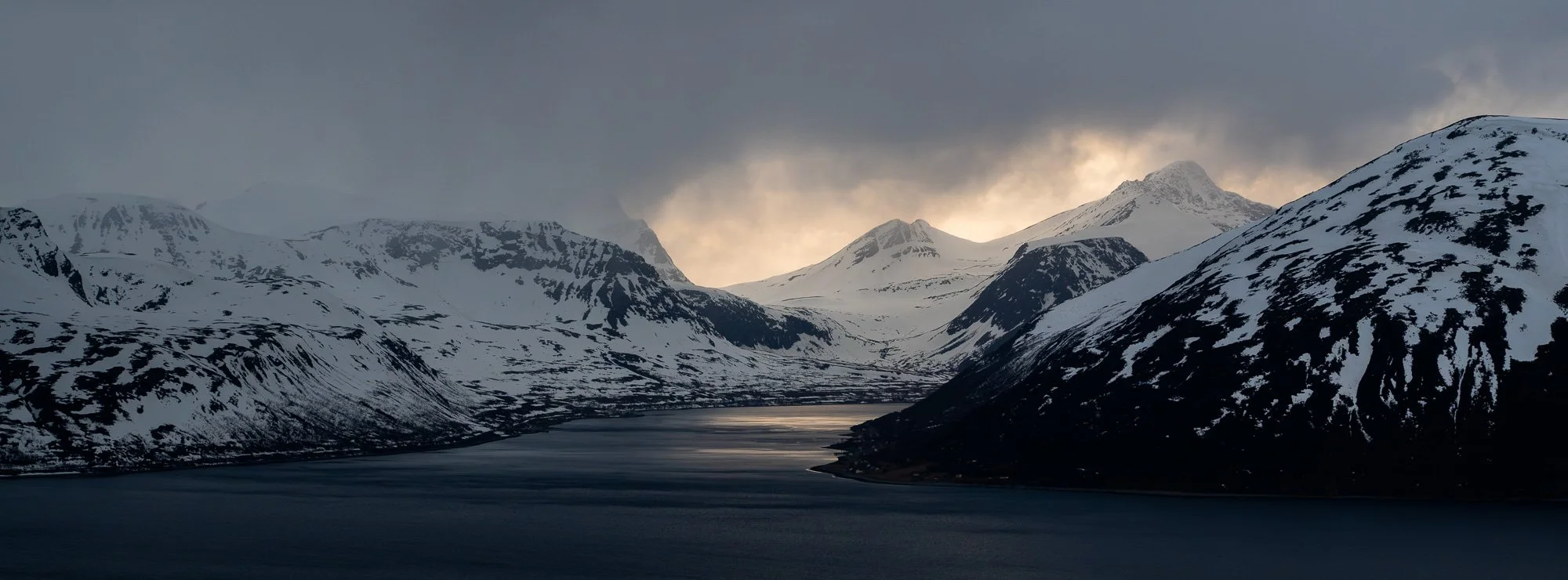 Montagnes enneigées autour d'un lac sous un ciel sombre
