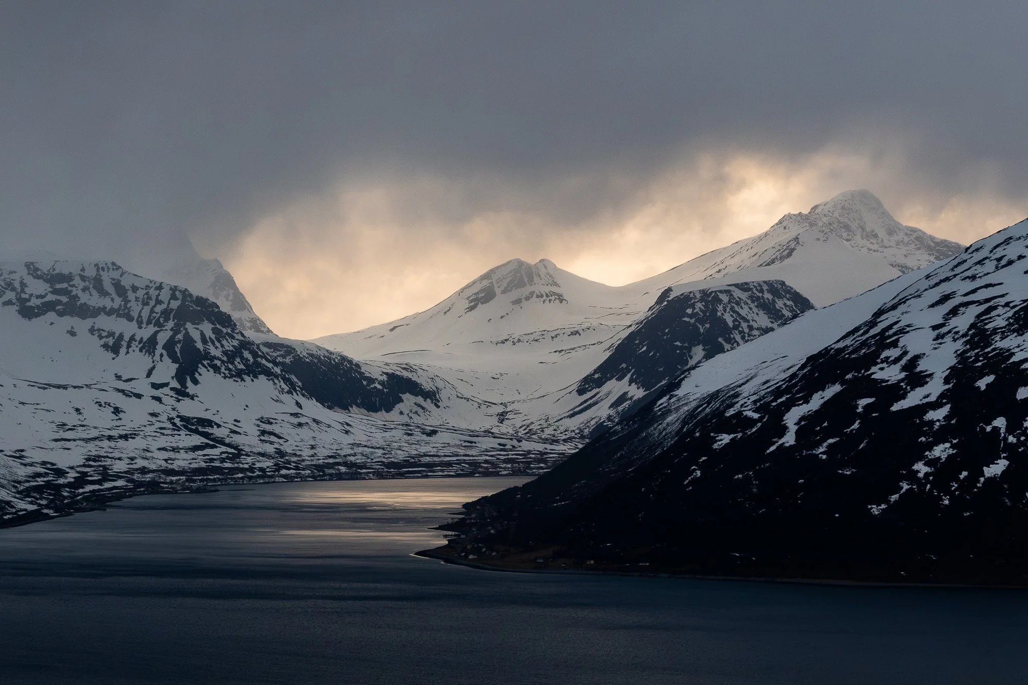 Montagnes enneigées sous un ciel nuageux avec un lac gelé au premier plan