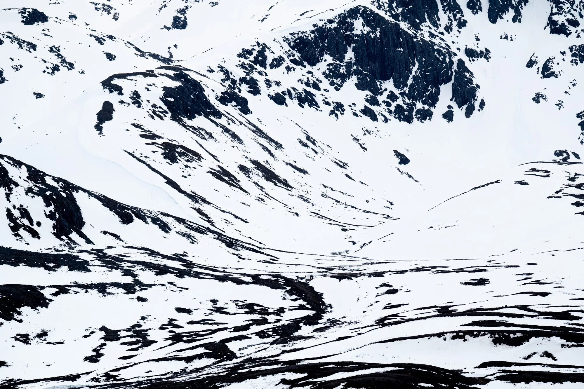 Montagnes enneigées avec des rochers noirs et des pentes enneigées dans un paysage de haute montagne.