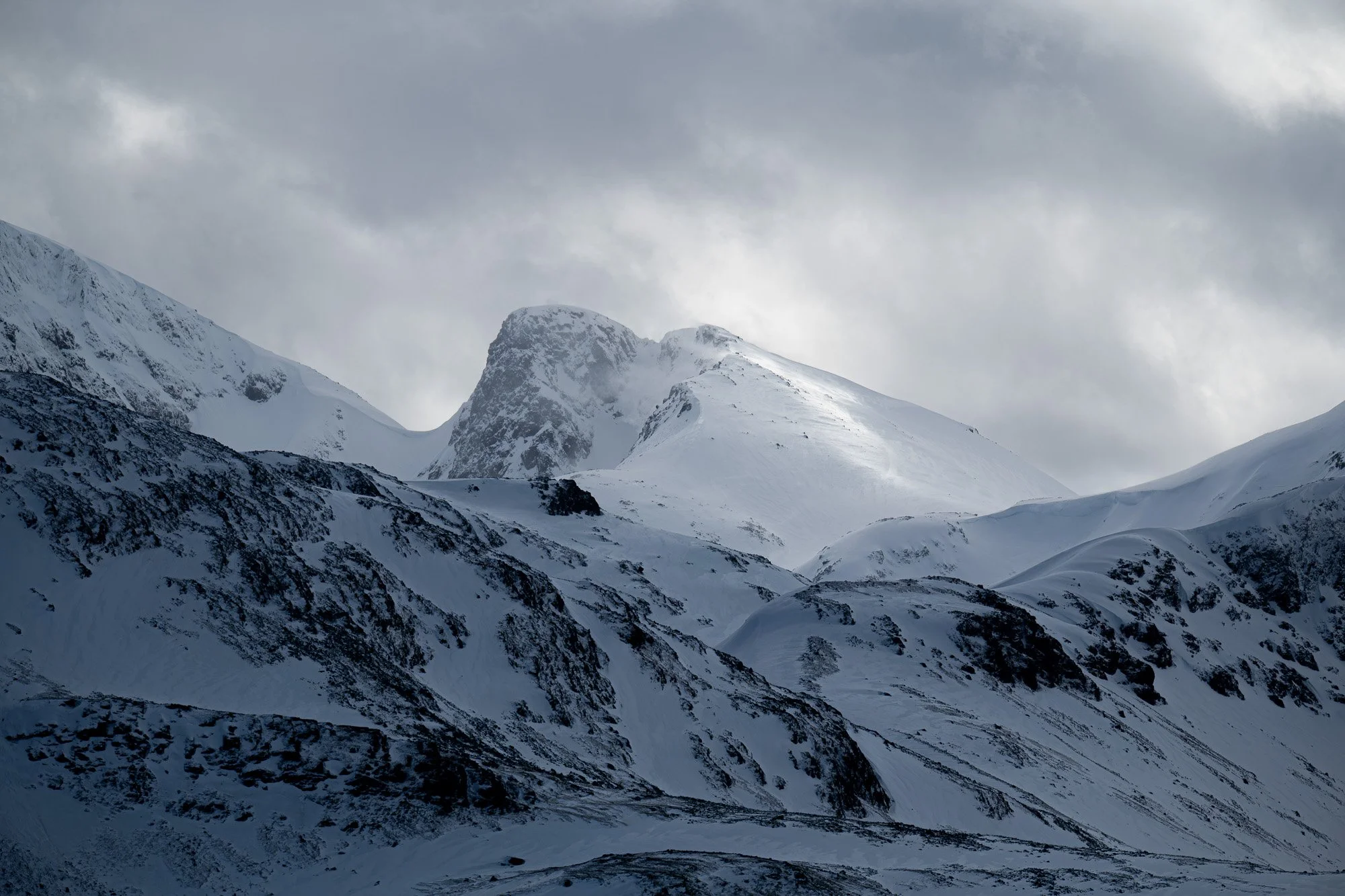Montagnes enneigées sous un ciel nuageux.