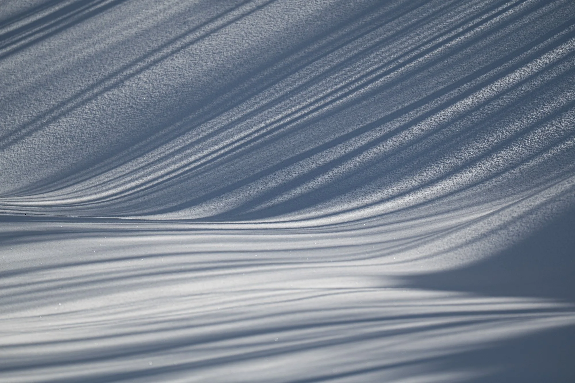 Traces d'ombre dans la neige créant des lignes parallèles.