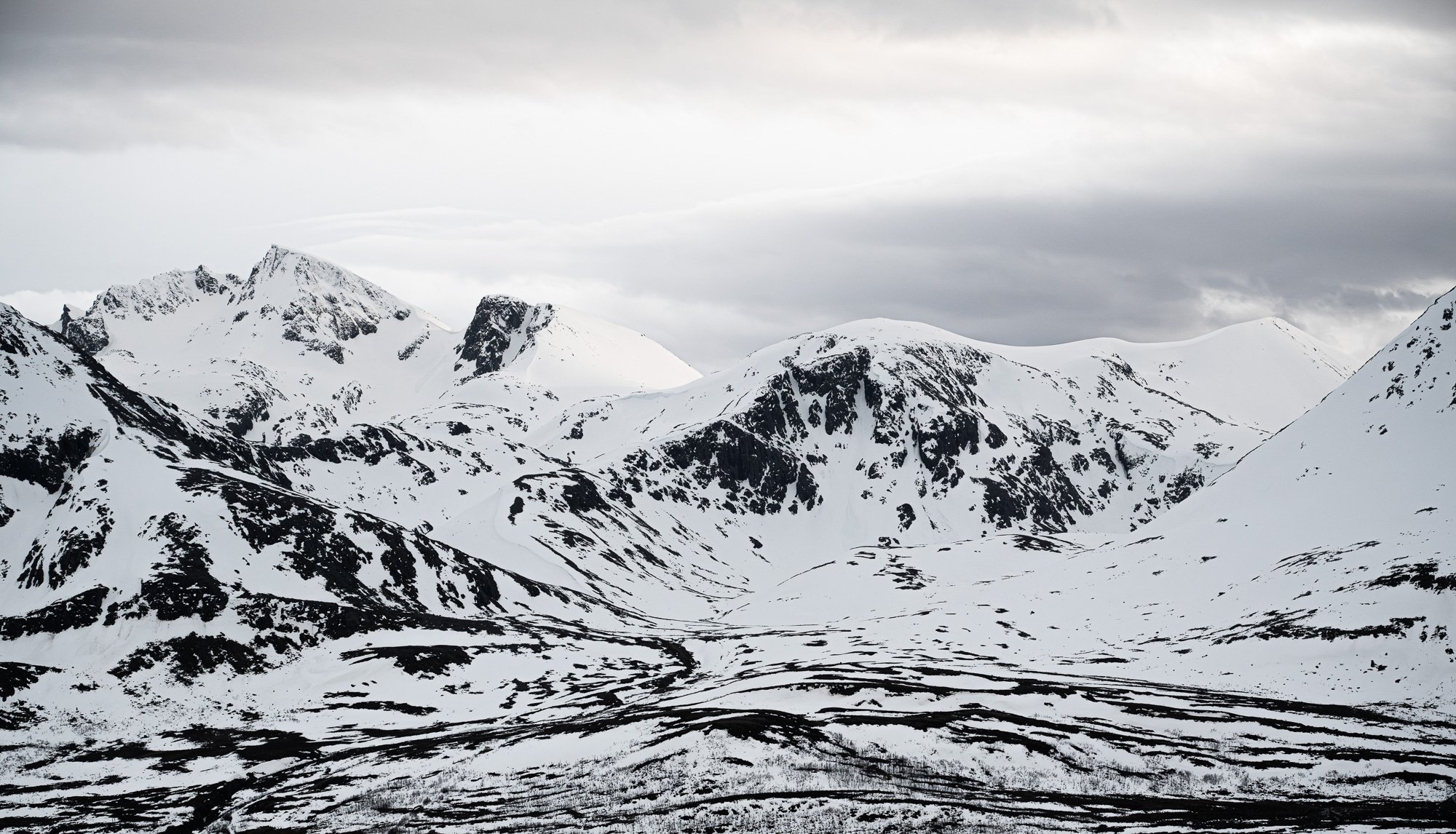 Montagnes enneigées sous un ciel nuageux.