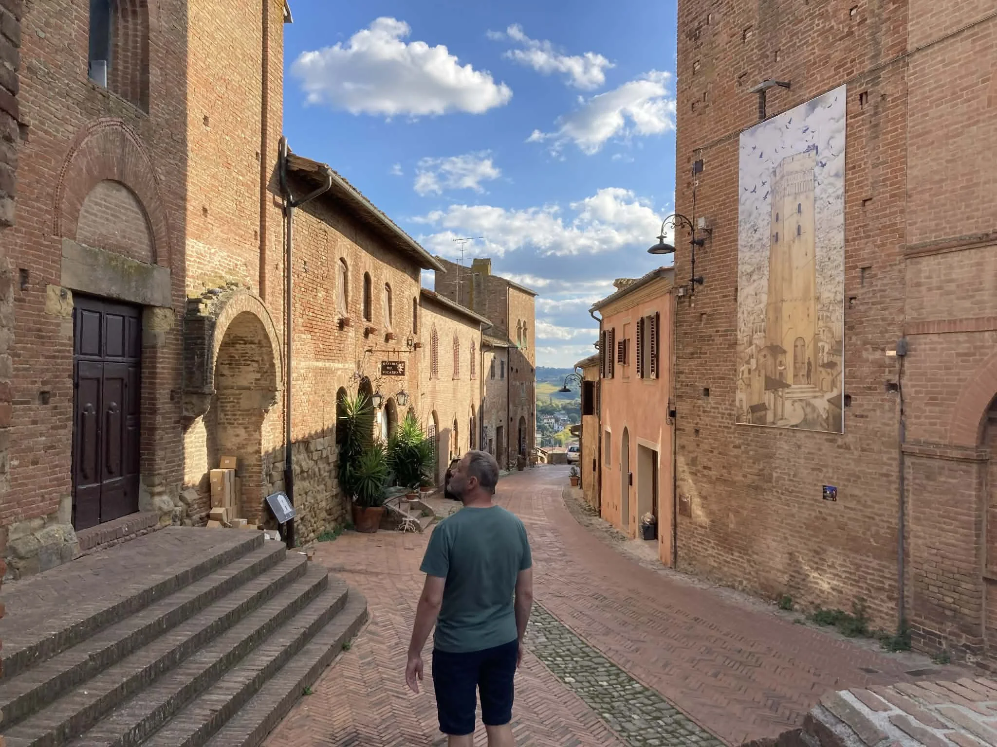 A man walking through a narrow historic street in Certaldo, Tuscany, Italy.