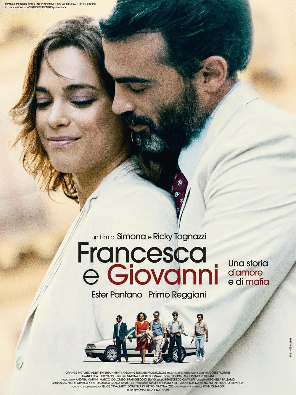 Affiche du film "Francesca e Giovanni", montrant deux personnages principaux, un homme et une femme, très proches. La femme a des cheveux châtains et sourit doucement, tandis que l'homme a une barbe sombre et regarde tendrement. En dessous, une scène avec cinq personnes debout près d'une voiture, dans un décor de nature.