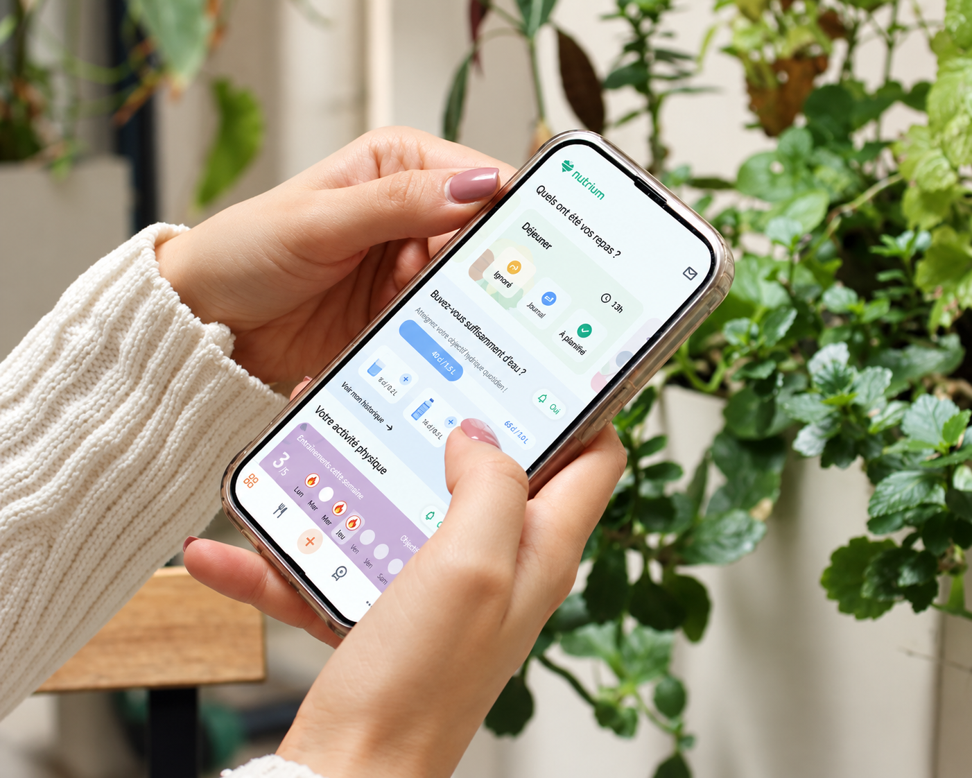 Une personne tenant un téléphone intelligent affichant une application de suivi de santé et de nutrition, avec des plantes vertes en arrière-plan.