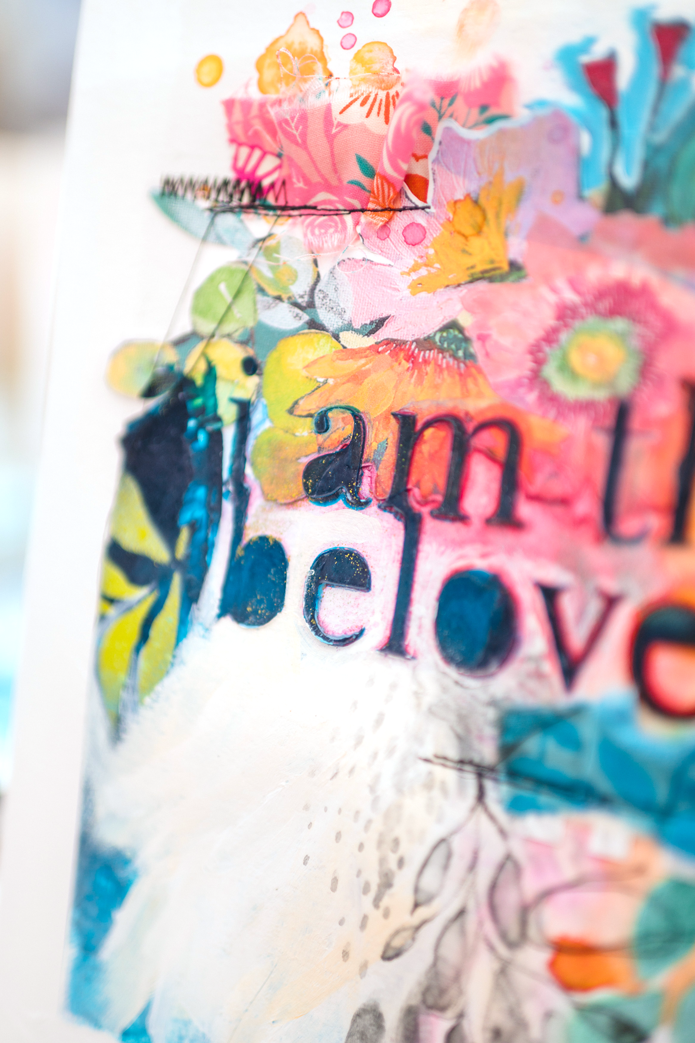 Close-up of a colorful, painted surface with floral and abstract designs, featuring the partial word 'peace' in black letters.