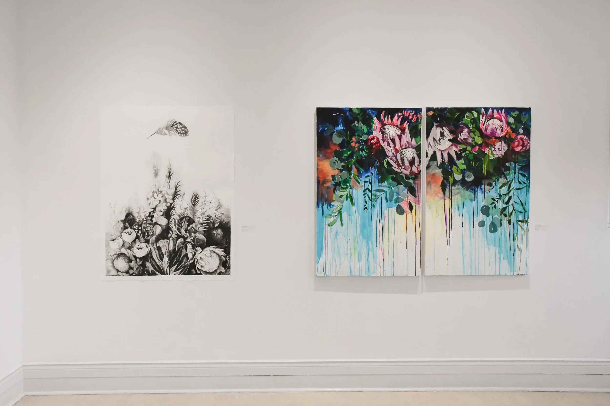 Two large paintings on a white gallery wall, one in black and white with floral and insect motifs, the other colorful with abstract flowers and dripping paint.