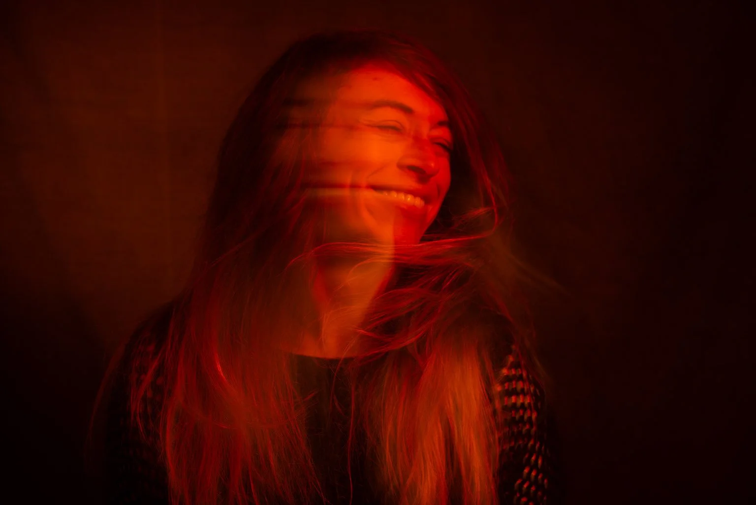 Smiling woman moving her head while lit by a red light