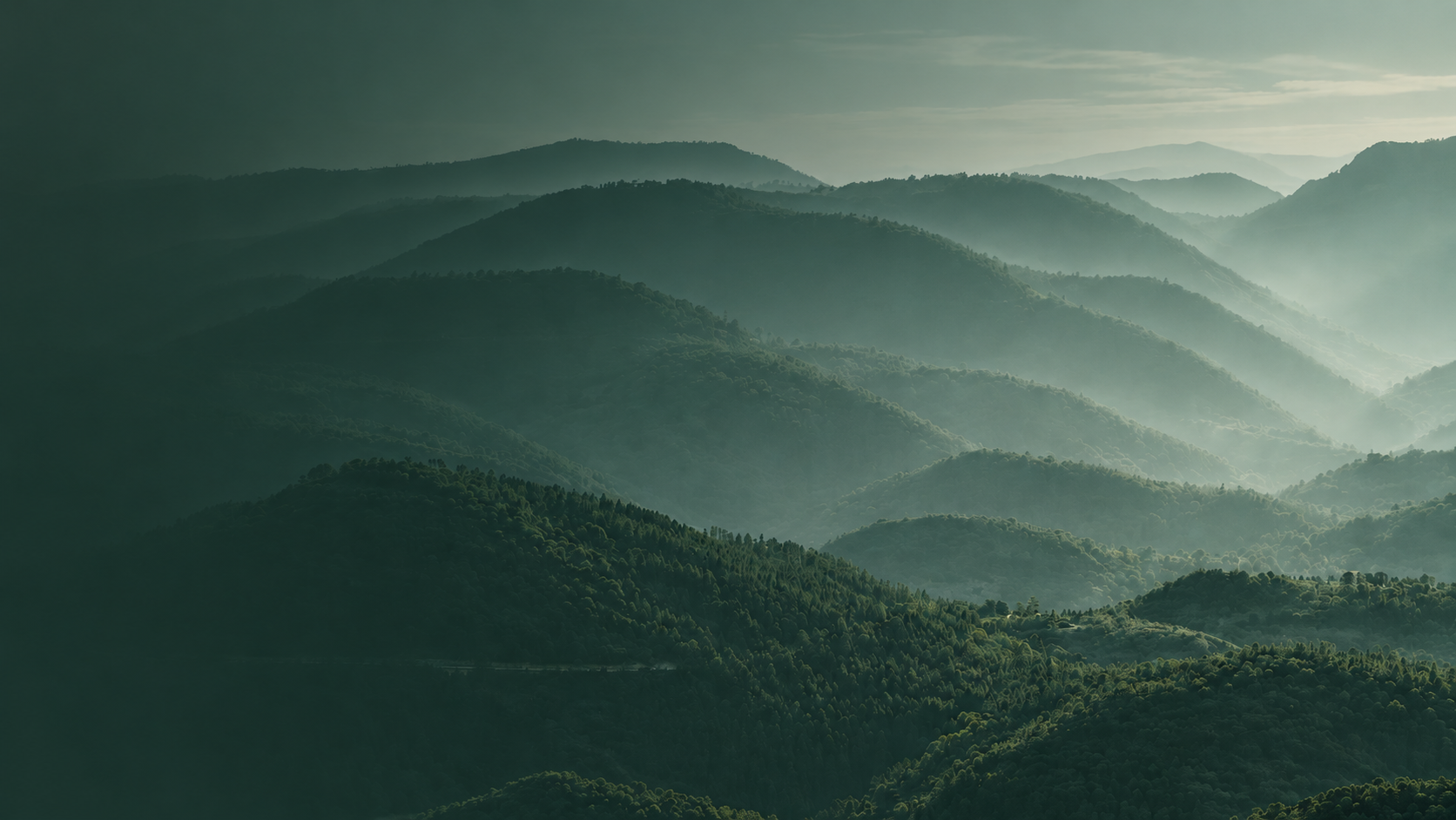 Layered green mountains with mist and fog, creating a serene landscape