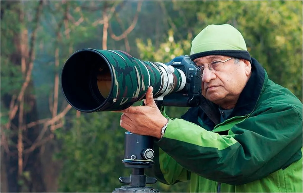 Nanak Dhingra in the field with his 600 mm lens, wearing a green jacket