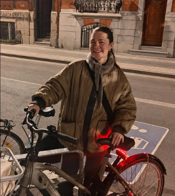 Smiling woman standing with a bicycle at night on a city street